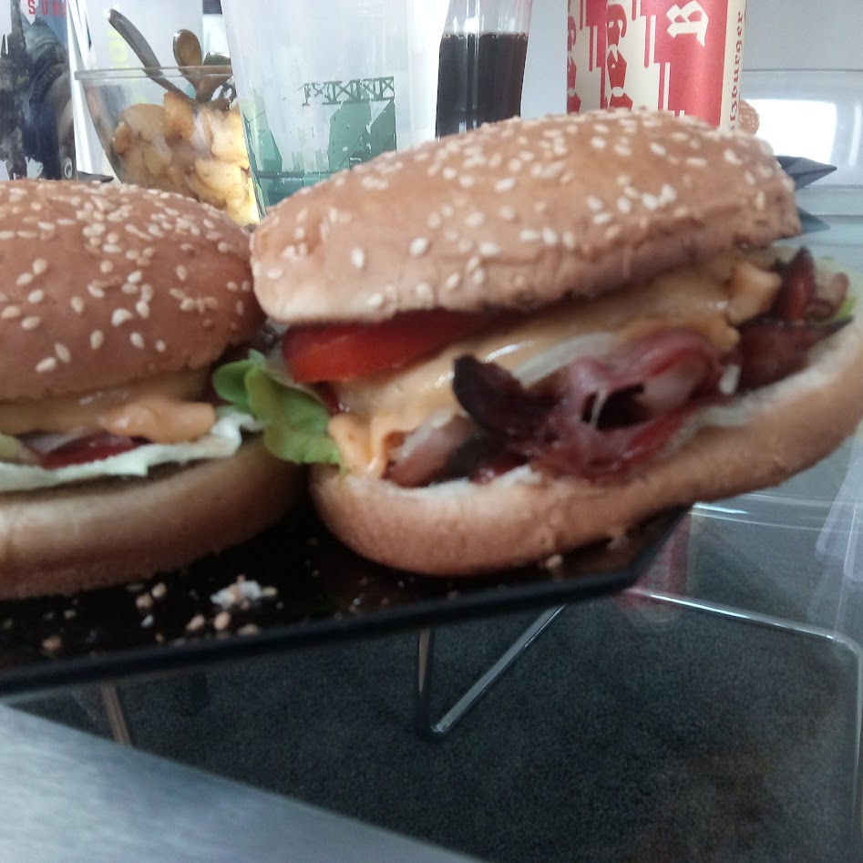 Zwei unkomplizierte Burger mit Sesam-Buns, Käse, Salat und Bacon